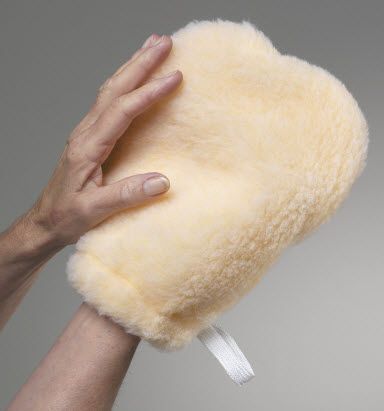 Hand holding a fluffy yellow pillow against a gray background