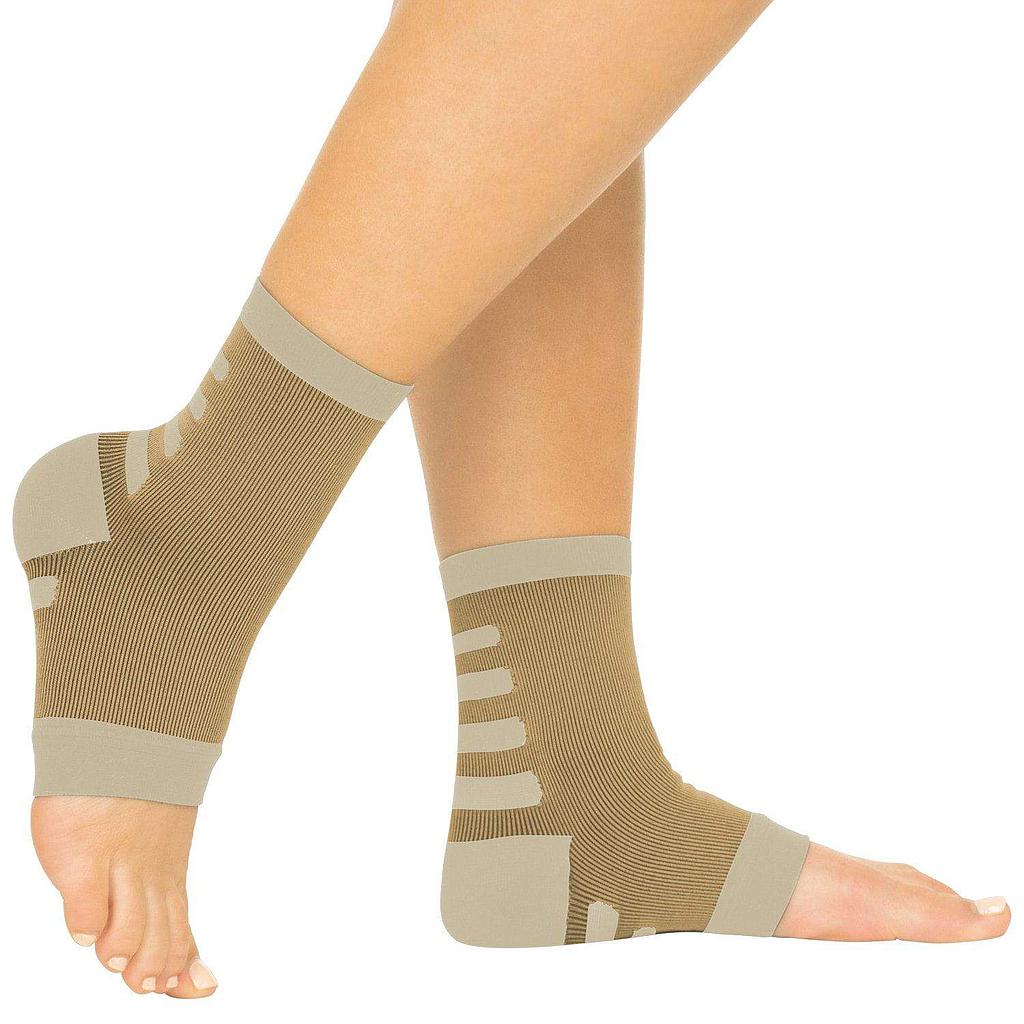 Beige compression ankle sleeves on a person's legs with a white background