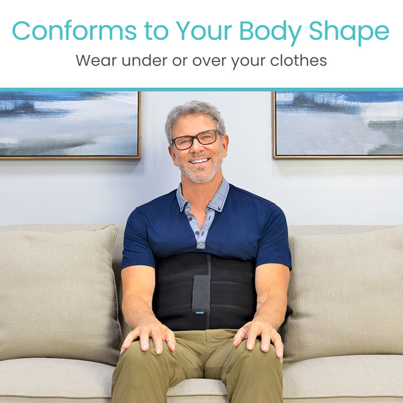 Man sitting on a couch wearing a black compression garment with text 'Conforms to Your Body Shape' and 'Wear under or over your clothes'.