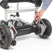 Close-up of a wheelchair's undercarriage with a hand adjusting a component on a white background