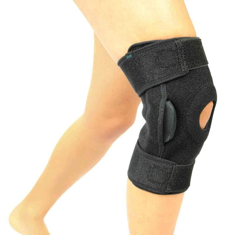 Black knee brace on a person's knee with a white background