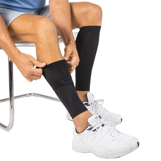 Person wearing black compression sleeves on their legs, sitting on a chair.