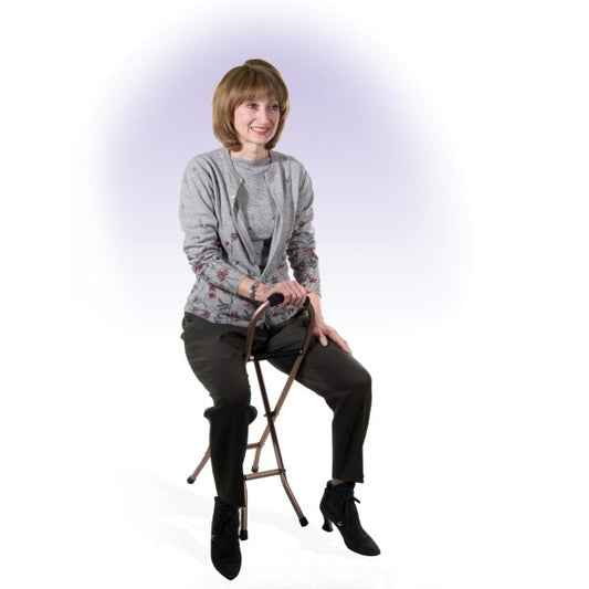 Person sitting on a stool wearing a gray sweater and black pants against a white background
