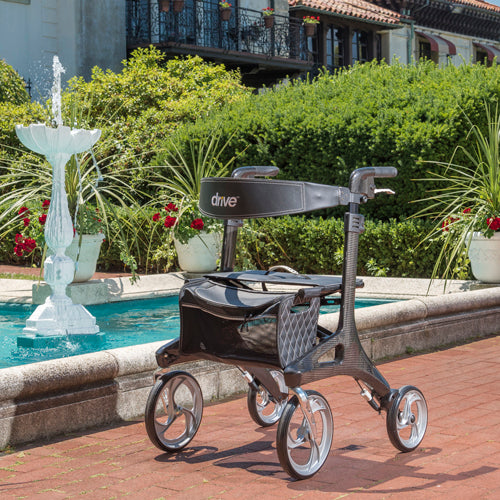 Rollator with 'Drive' branding in an outdoor setting with a fountain and greenery.