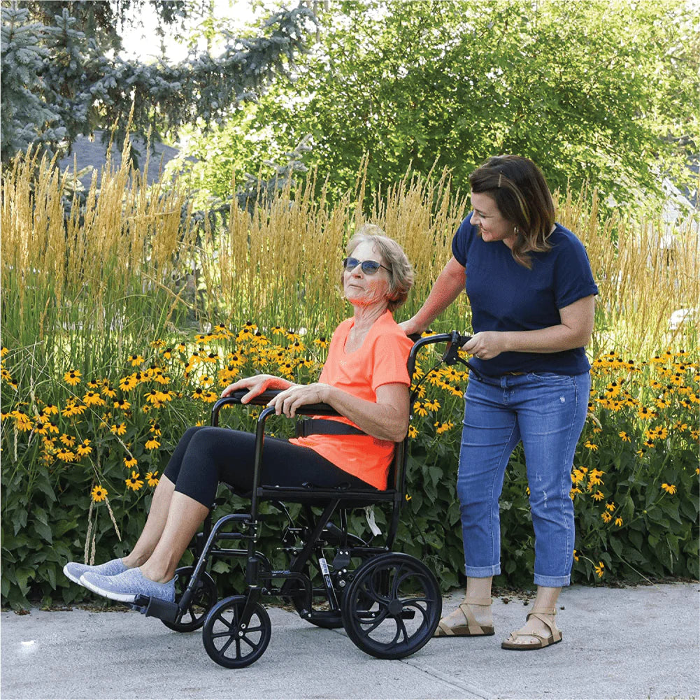 Woman pushing a seated woman in a wheelchair through a garden with yellow flowers and greenery.