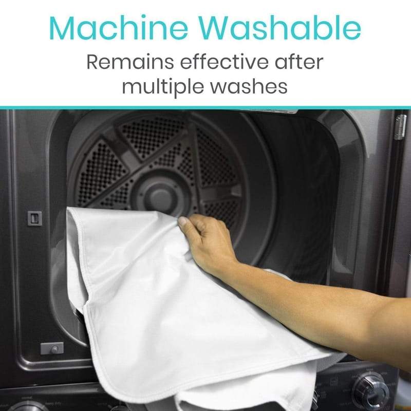 Hand placing a white towel into a dryer with text indicating machine washability.
