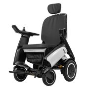A modern power wheelchair with a black seat, black armrests, and a white side panel, shown from a three-quarter angle against a solid white background.
