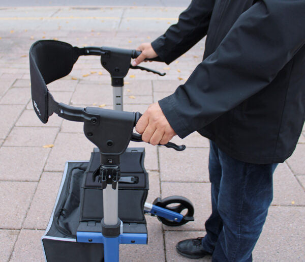 Person holding a mobility scooter on a paved surface