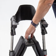 Person adjusting a black and gray high chair on a white background
