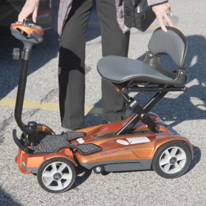 Gold mobility scooter with a seat on a paved surface