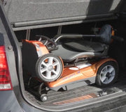Gold mobility scooter being loaded into a car trunk