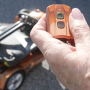 Hand holding a remote with a blurred scooter in the background