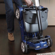 Person using a blue mobility scooter on a wooden floor.