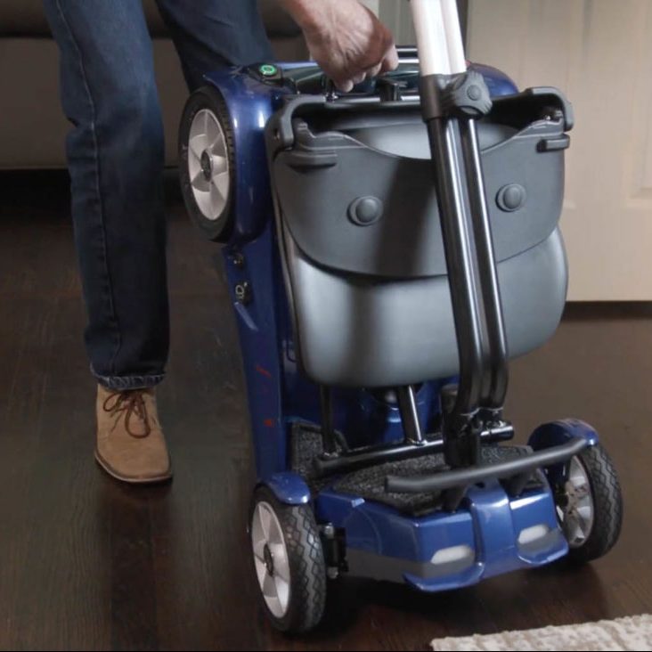 Person using a blue mobility scooter on a wooden floor.