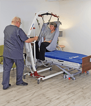caregiver putting patient on bed with lift