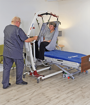 caregiver putting patient on bed with lift