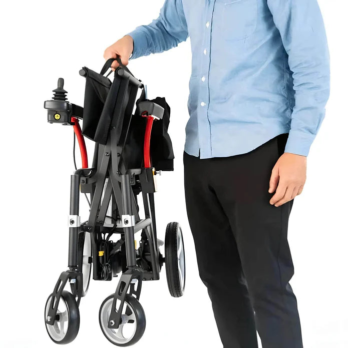 Person holding a folded black and red mobility scooter on a white background