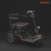 Black mobility scooter with a seat and red accents on a dark background, branded 'Feather'.