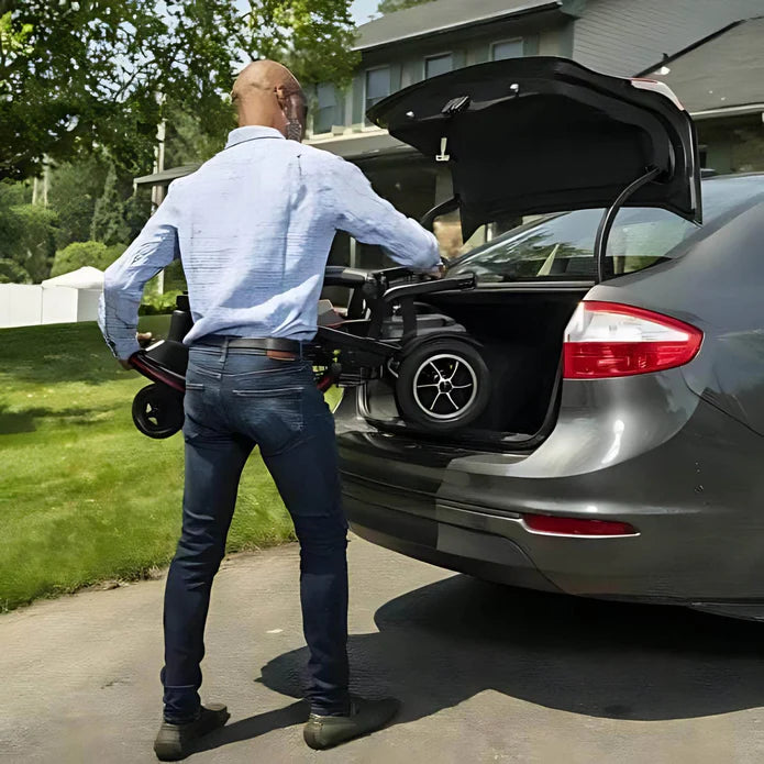 Man loading a golf cart into the trunk of a car in a driveway.