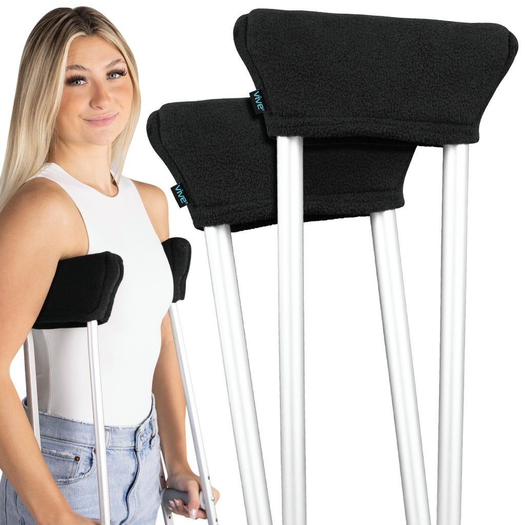 Woman holding crutches with black arm pads on a white background