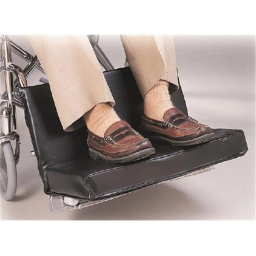 Wheelchair with a footrest extension showing a person's feet wearing brown shoes.