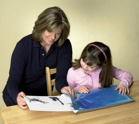 Woman and young girl looking at a book together at a table.
