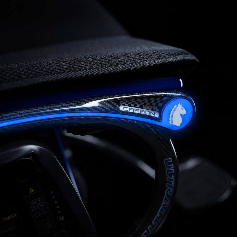 Close-up of a carbon-fiber armrest with a glowing blue LED light strip and a circular blue logo featuring a white horse head, set against a dark interior background.