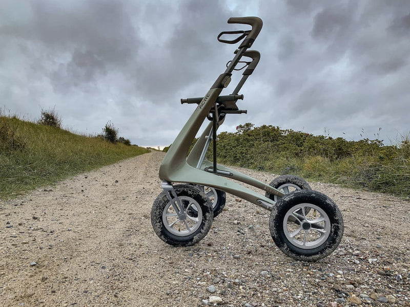 Rollator on a gravel path with grass and trees in the background