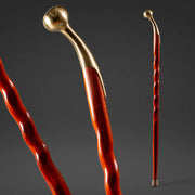 Two walking canes with gold and red handles on a dark background