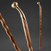 Two wooden walking sticks with brass handles on a dark background