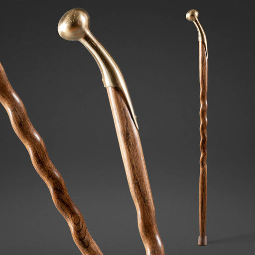 Two wooden walking sticks with brass handles on a dark background