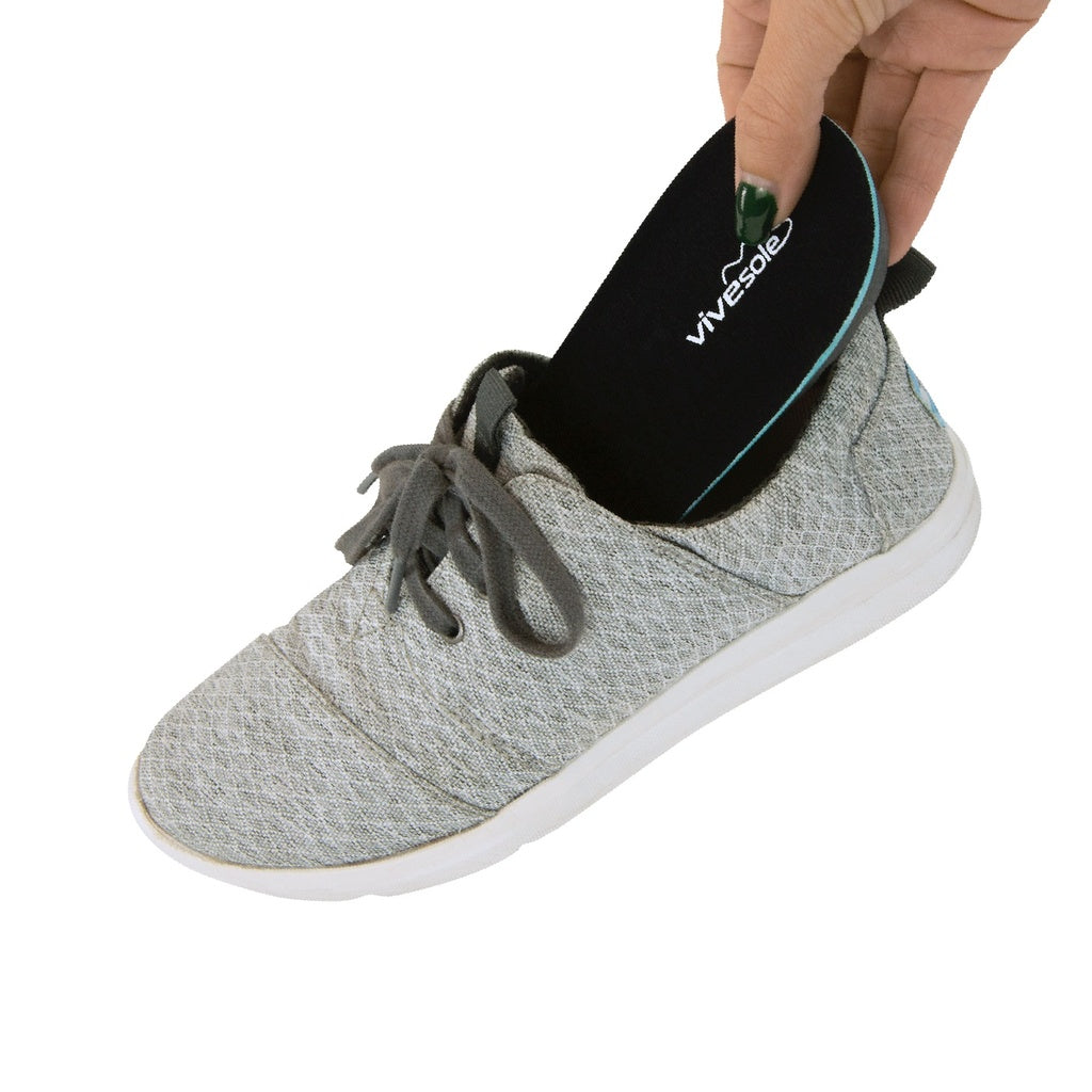 Gray sneaker with a black insole labeled 'Vivesole' being inserted into the shoe.
