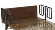 A close-up of a metal bed frame with dark brown wooden headboard and footboard panels, black metal side rails, and a perforated metal slatted base.