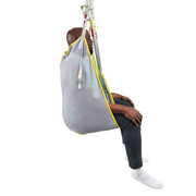 A person seated in a gray mesh suspension sling chair with yellow trim, suspended from white straps against a plain white background.