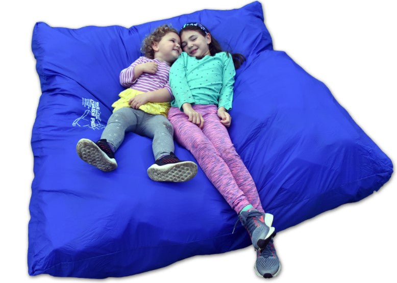Two children sitting on a large blue bean bag with a visible brand logo.