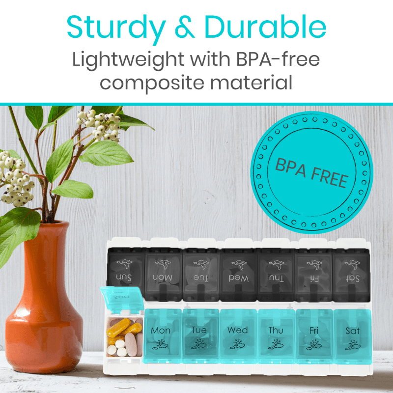Weekly pill organizer with BPA-free label next to a vase with flowers on a light wooden surface.