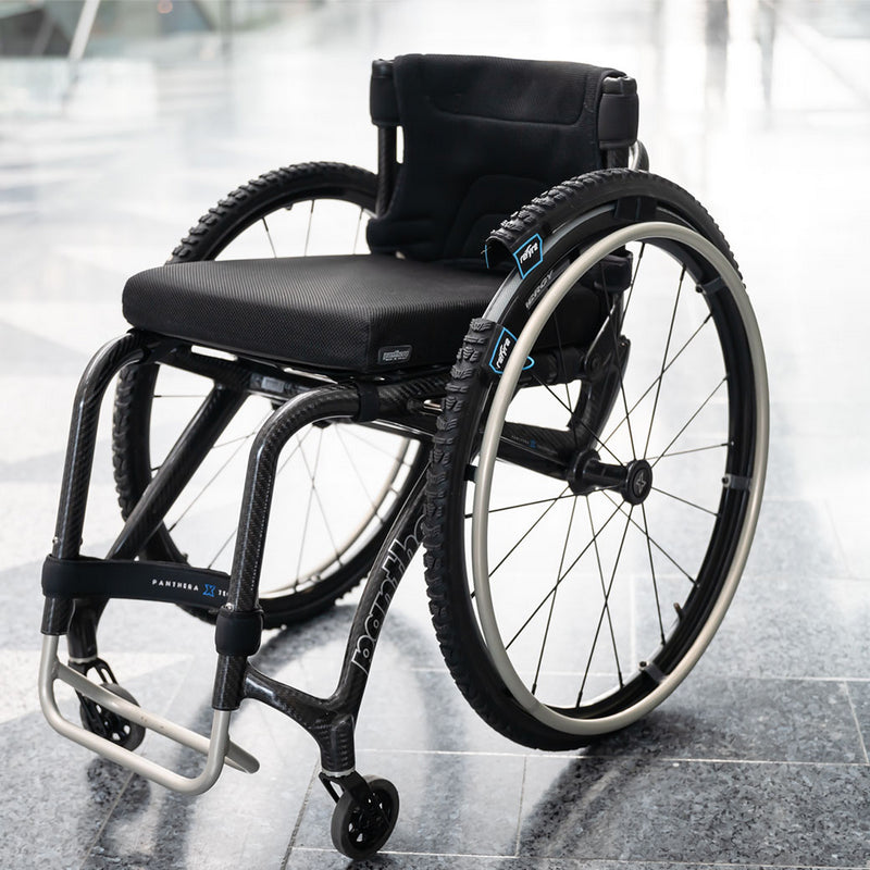 Black wheelchair with large wheels on a reflective floor