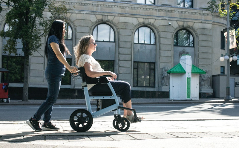 Two women using a mobility scooter on a city street.
