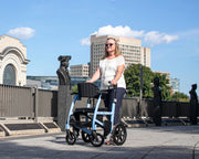Woman using a walker in an urban setting with statues and buildings in the background