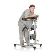 A person in a gray sweatshirt and sweatpants using a walker on a white studio background.