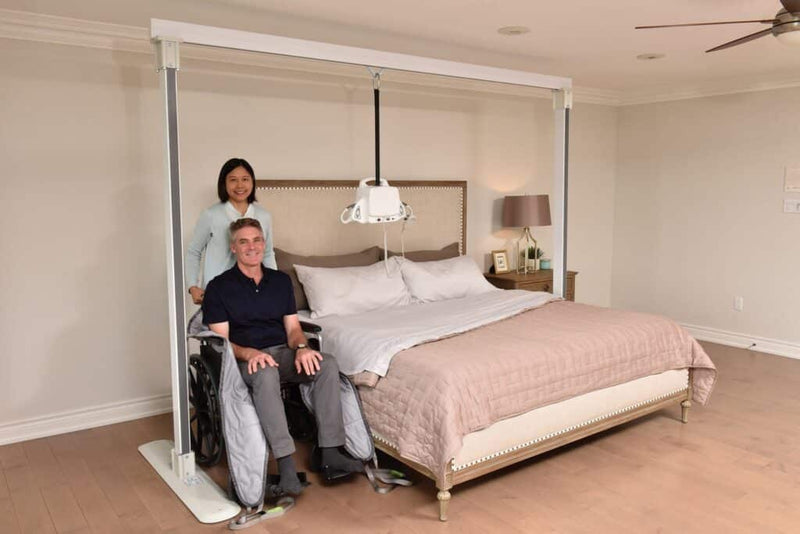 Two people in a bedroom with a bed and furniture.