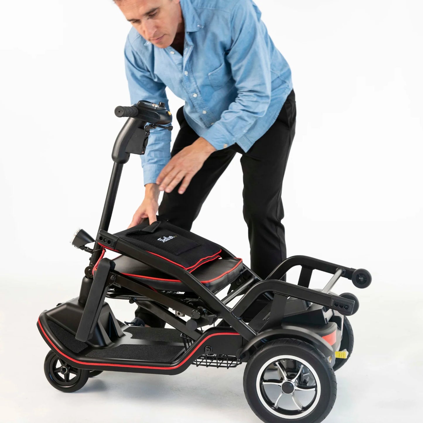 Person adjusting a black scooter with red accents on a white background