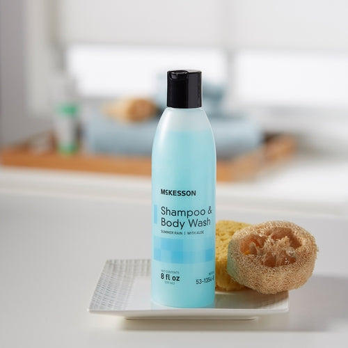 Blue McKesson shampoo and body wash bottle with a loofah on a blurred bathroom background