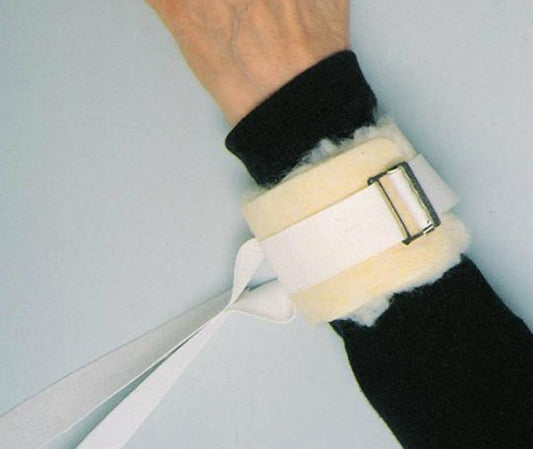 Close-up of a person's wrist wearing a black wristband and a white bandage with a metal clip on a light gray background.