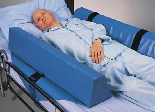 Person lying in a hospital bed with a blue safety rail.