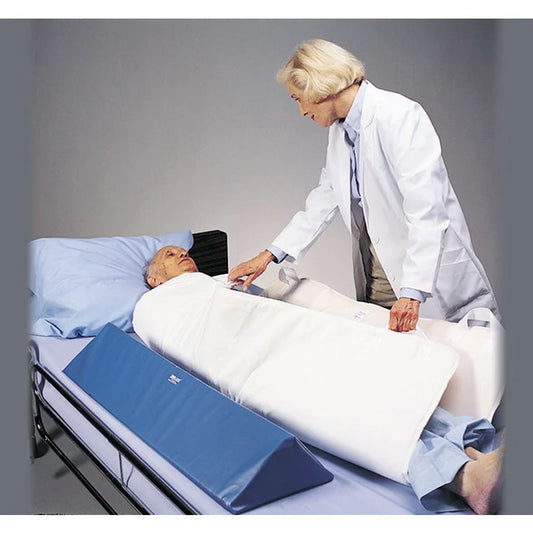 Doctor attending to a patient lying on an inflatable bed wedge in a clinical setting.