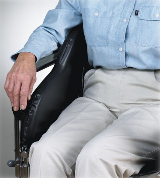 Person wearing a light blue shirt and beige pants sitting in a wheelchair.