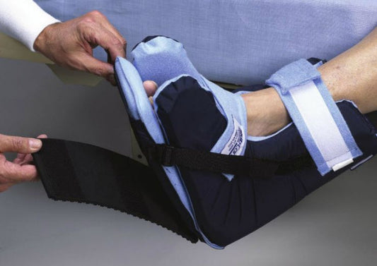Hand applying a black and blue cast to a person's arm on a gray surface.
