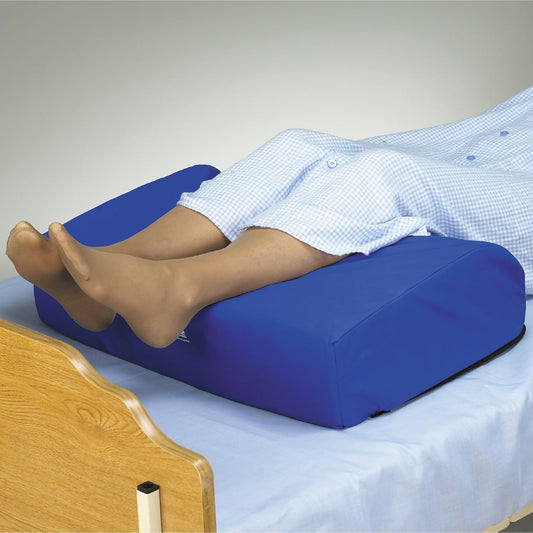 Person lying on a blue wedge pillow in a bedroom setting.