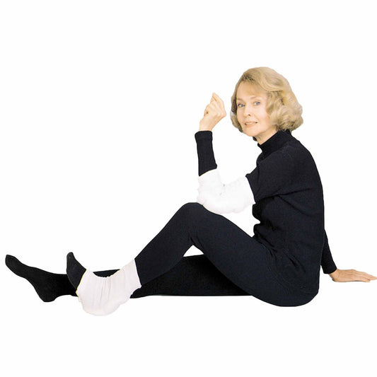 Woman sitting on the floor wearing a black outfit with white gloves and socks.